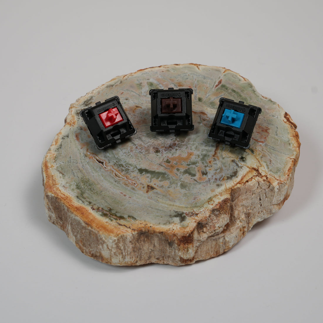 Cherry MX Red, Cherry MX Brown, and Cherry MX Blue switches side by side representing linear, tactile, and clicky switch types