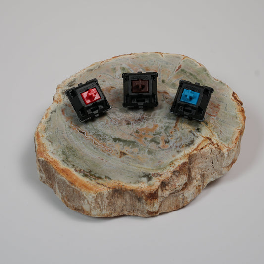 Cherry MX Red, Cherry MX Brown, and Cherry MX Blue switches side by side representing linear, tactile, and clicky switch types