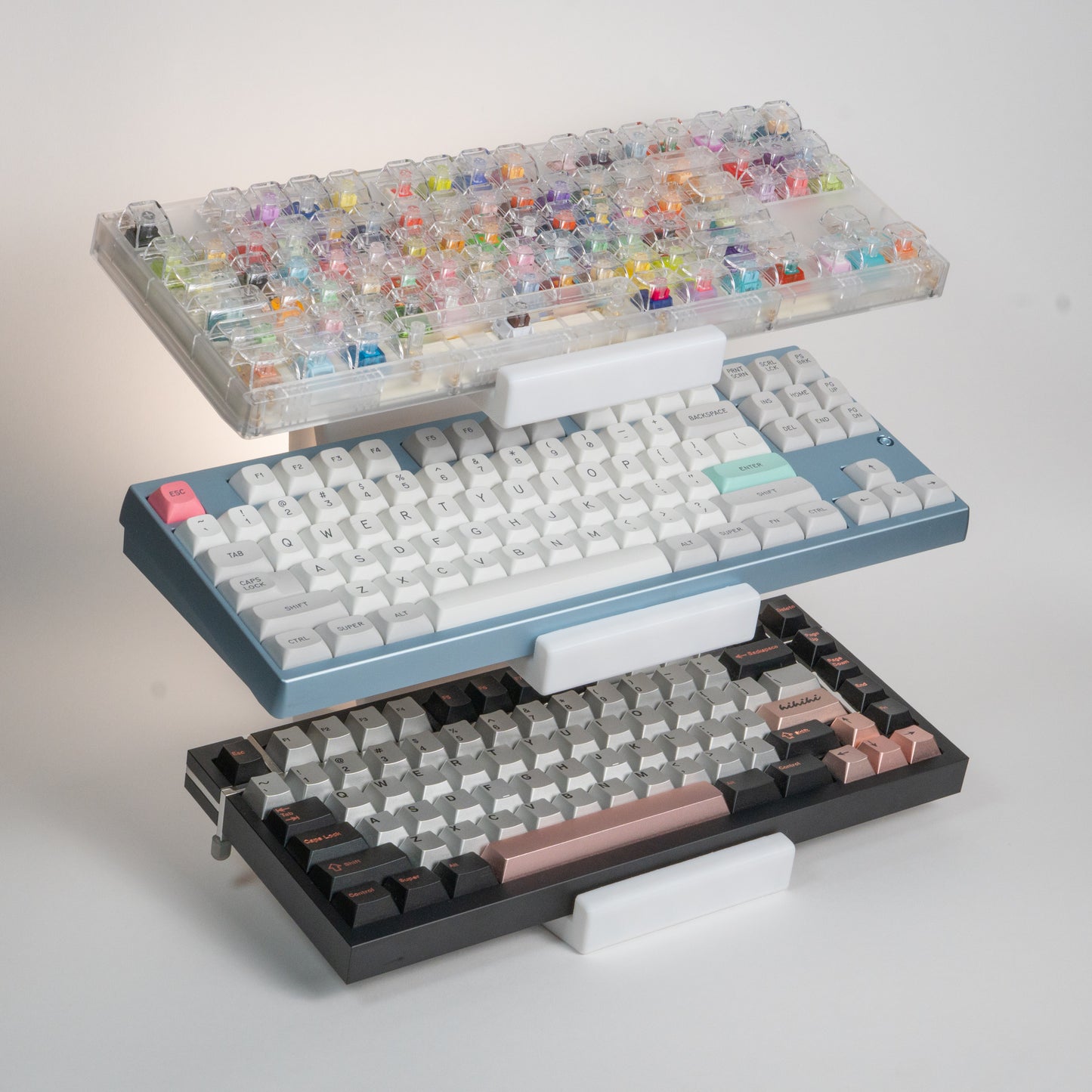 White 3-tier keyboard stand holding a switch tester keyboard, a baby blue Neo80, and a Box75