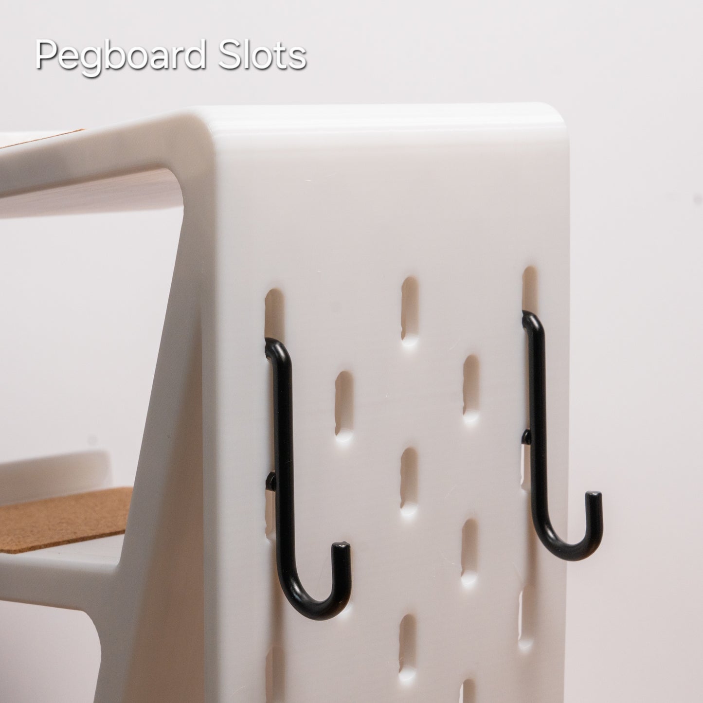 Pegboard slots on the back of a white keyboard stand with two black Skadis hooks attached